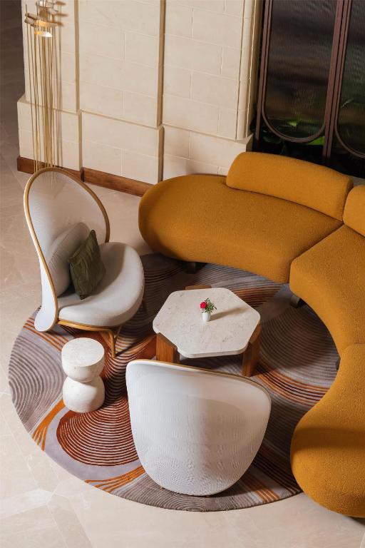 a room with a couch and chairs on a rug at Kempinski Hotel San Lawrenz in San Lawrenz