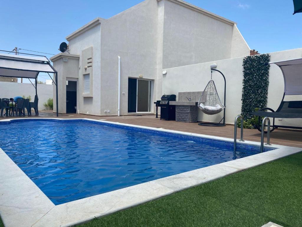 a swimming pool in front of a house at Villa avec piscine à Djerba in Al Maqārisah