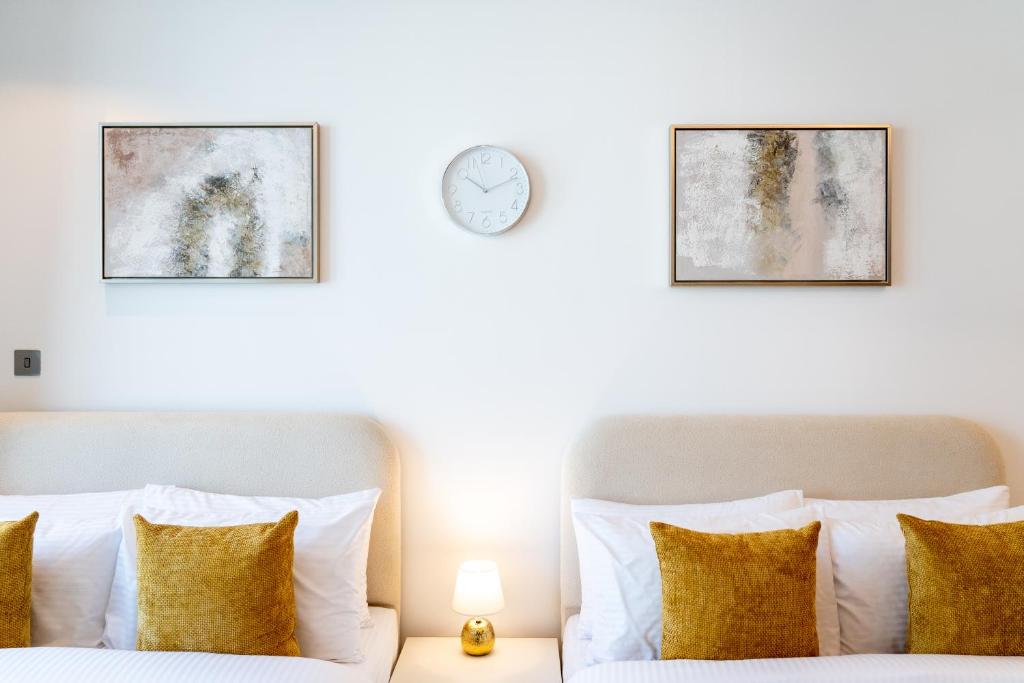 ein Schlafzimmer mit 2 Betten und einer Uhr an der Wand in der Unterkunft Chalet Homes - LUX New Studio With 2 Double Beds in Downtown Dubai in Dubai