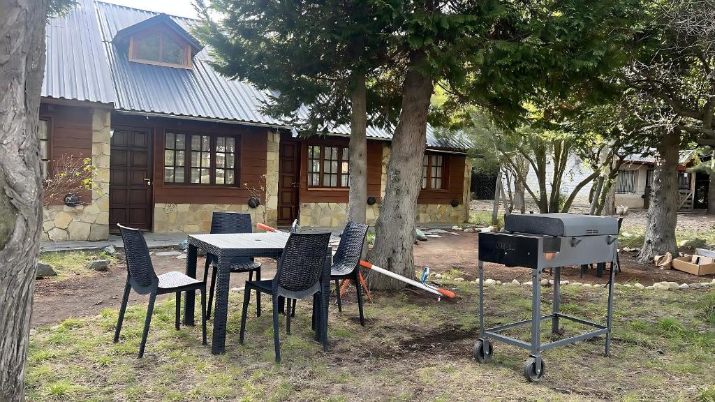 a table and chairs and a grill in front of a house at Complejo de Bungalows del Lago Km13 in San Carlos de Bariloche