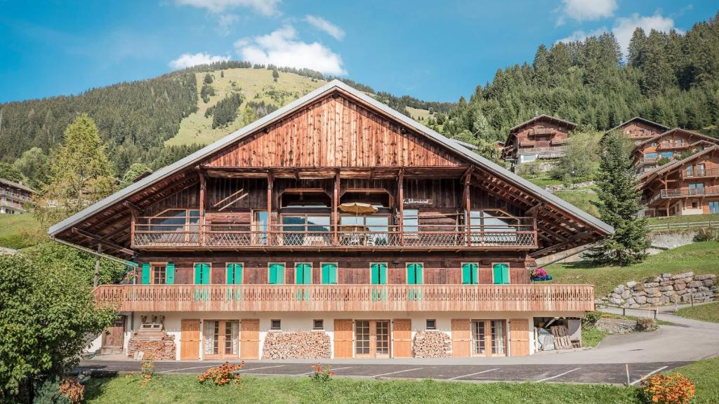un grand bâtiment en bois avec des fenêtres vertes et une montagne dans l'établissement Appartement spacieux à Châtel 120 m² avec terrasse privée, à Châtel