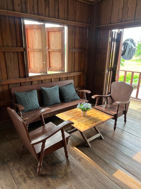 a living room with a couch and a table and a chair at Me Vadsana Homestay in Ban Mae Khachan (1)