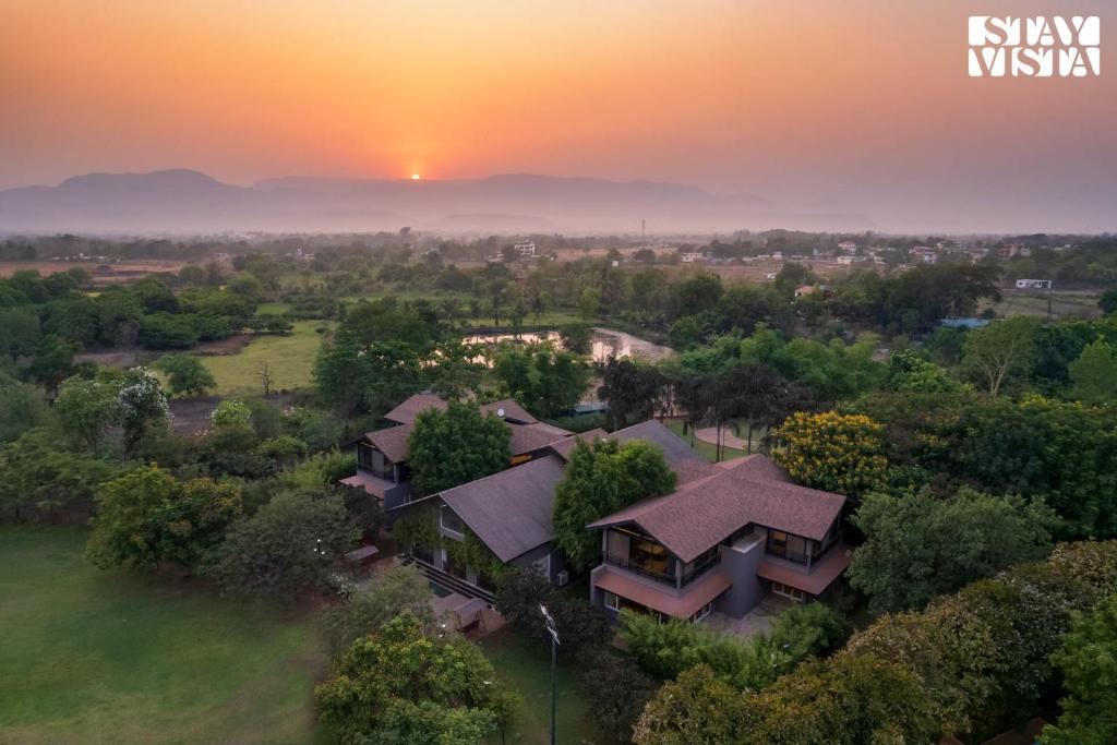 eine Luftansicht eines Hauses mit Sonnenuntergang im Hintergrund in der Unterkunft Nivaant Farms & Cottages - Nestled in lush greenery, offering a Swimming pool, Orchard, Jacuzzi & A spacious lawn with gazebo in Karjat