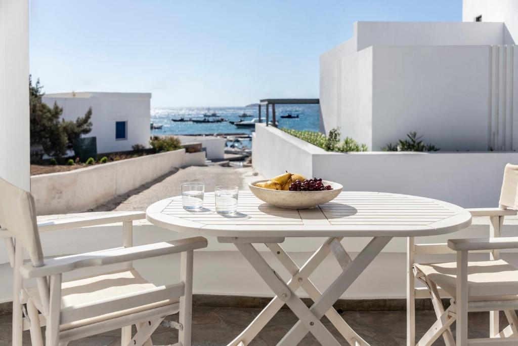 a white table with a bowl of fruit on a balcony at Om Living Milos in Pollonia
