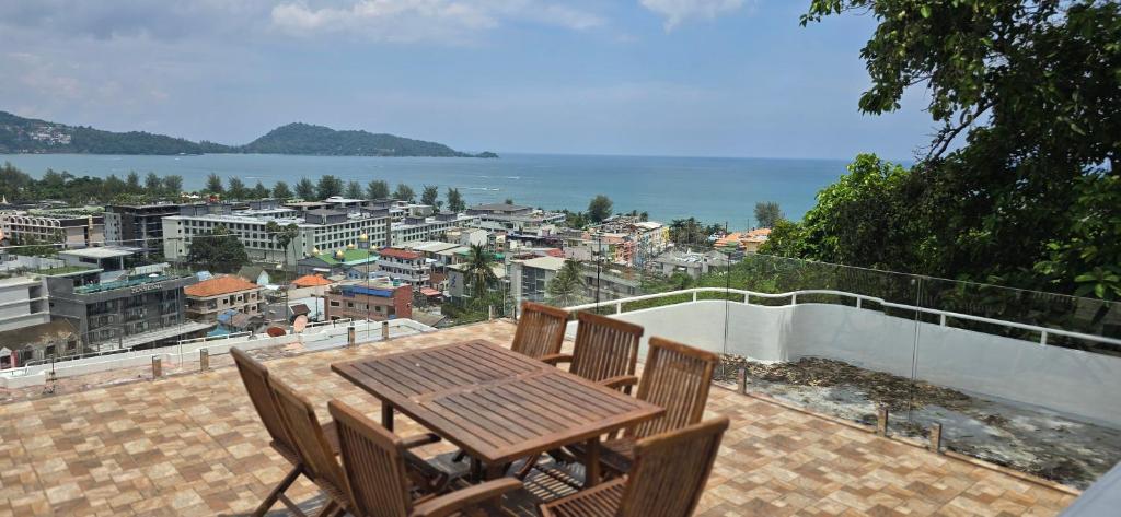 a wooden table and chairs on a patio with a view at Andaman Seaview house rooftop in Patong Beach