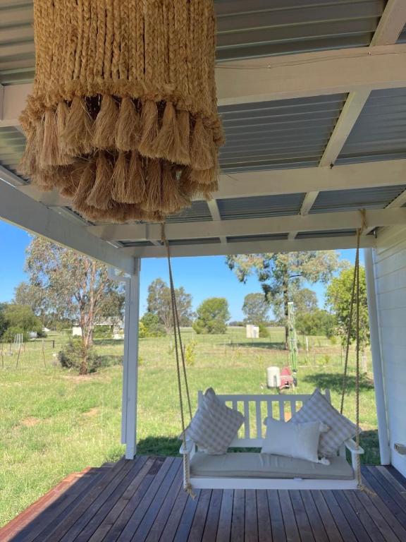 a swing on a porch with a view of a field at Dalton Farmstay in Ulupna West