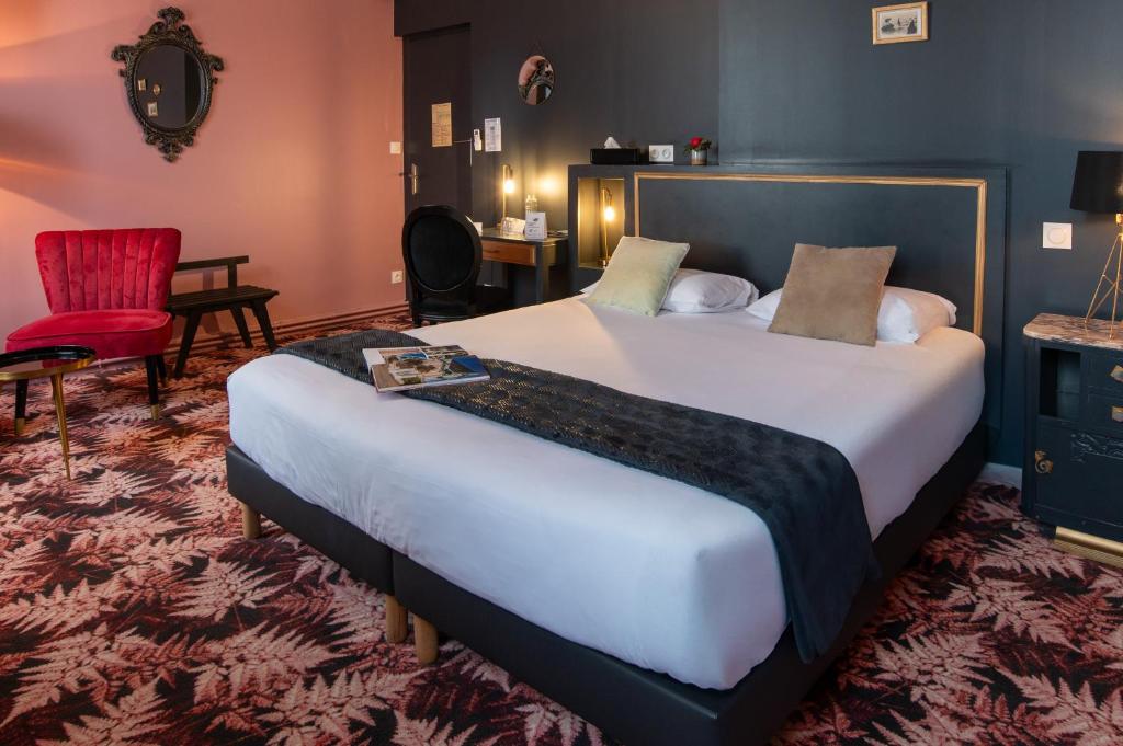 a hotel room with a large bed and a red chair at The Originals Boutique, Hôtel Victoria, Châtelaillon-Plage in Châtelaillon-Plage