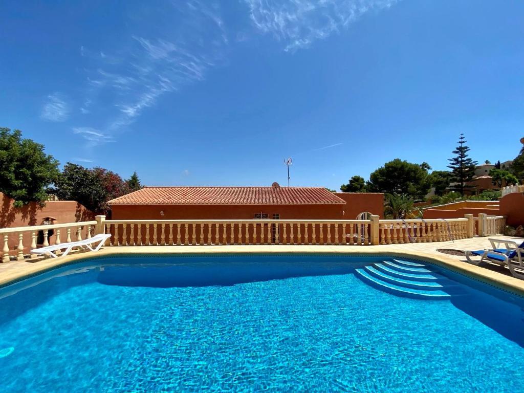 a large blue swimming pool next to a wooden fence at Villa June in Benitachell