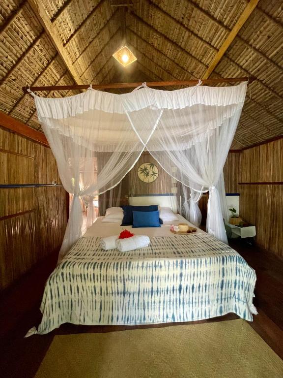 a bedroom with a bed with a mosquito net at Ravenala Lodge, Bungalow et Maison Ile aux Nattes in Ile aux Nattes