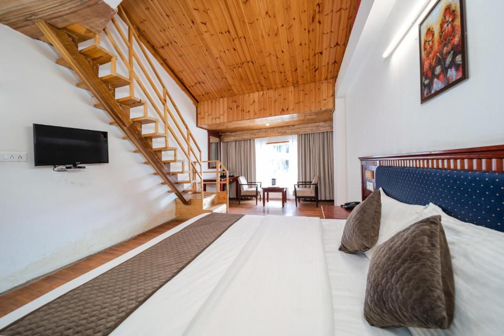 una grande camera da letto con un letto e una scala di Hotel Monal a Manāli