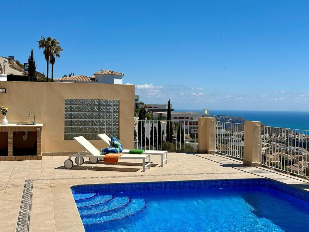 een zwembad met een stoel naast een gebouw bij Villa Paraíso in Benitachell