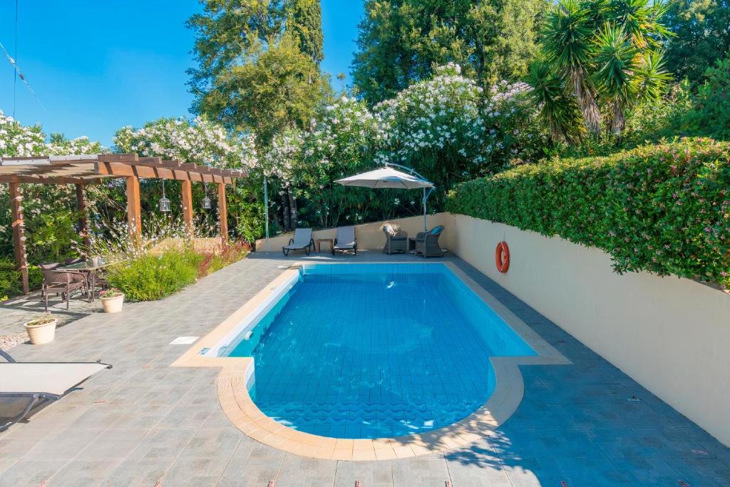 a swimming pool in a backyard with chairs and an umbrella at Blue Coast Suites - Seaside Retreat with Pool in Exclusive Kommeno in Kommeno