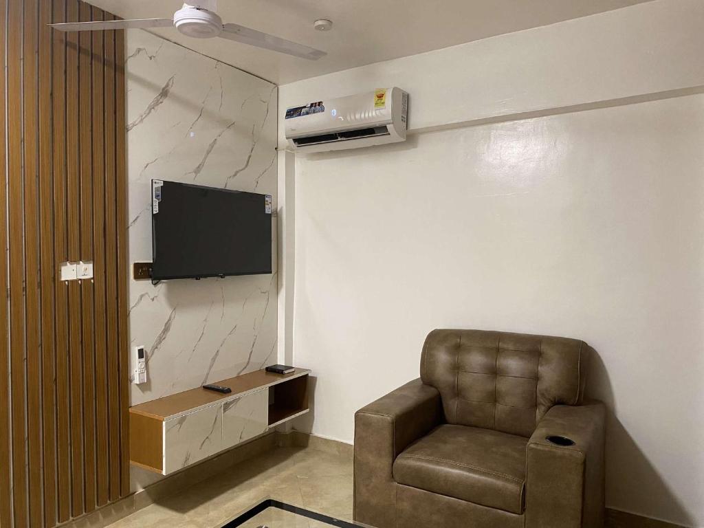 a living room with a chair and a flat screen tv at Adiepena Cozy Apartment- 5mins from KNUST & 7mins from Kumasi Airport in Kumasi