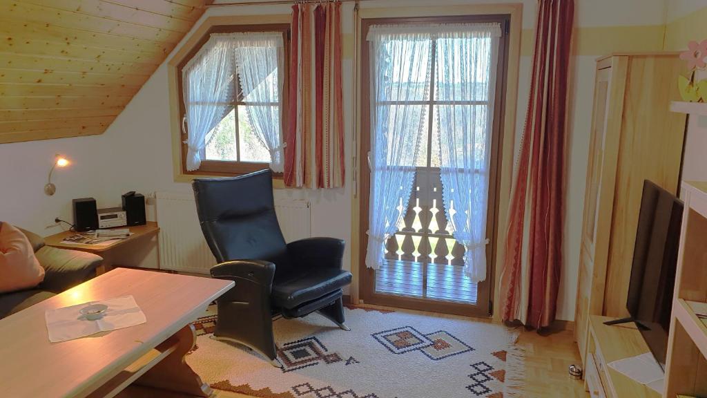 a living room with a chair and a desk and windows at Wohnung Fübüüni in Wittenschwand