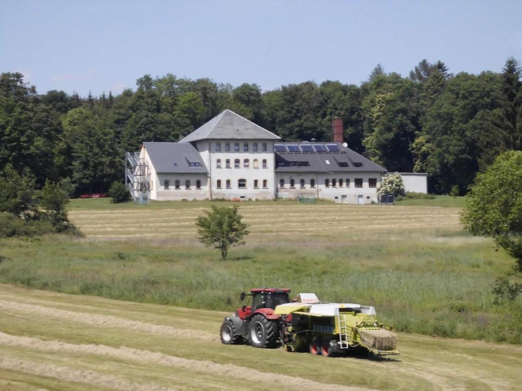 a tractor driving through a field in front of a large house at Ferienwohnung Für 4 Personen Ca 37 M Sup2 In Sayda, Mittelgebirge Deutschland Erzgebirge in Sayda