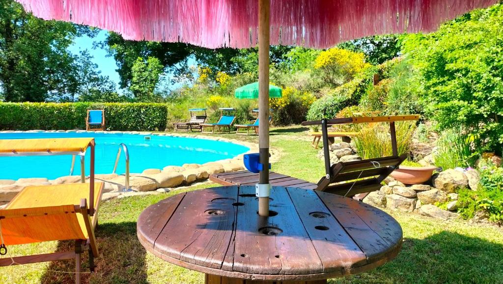 einen Holztisch mit einem Sonnenschirm neben einem Pool in der Unterkunft Ferienhaus für 10 Personen in Penna San Giovanni, Marken Provinz Macerata in Penna San Giovanni