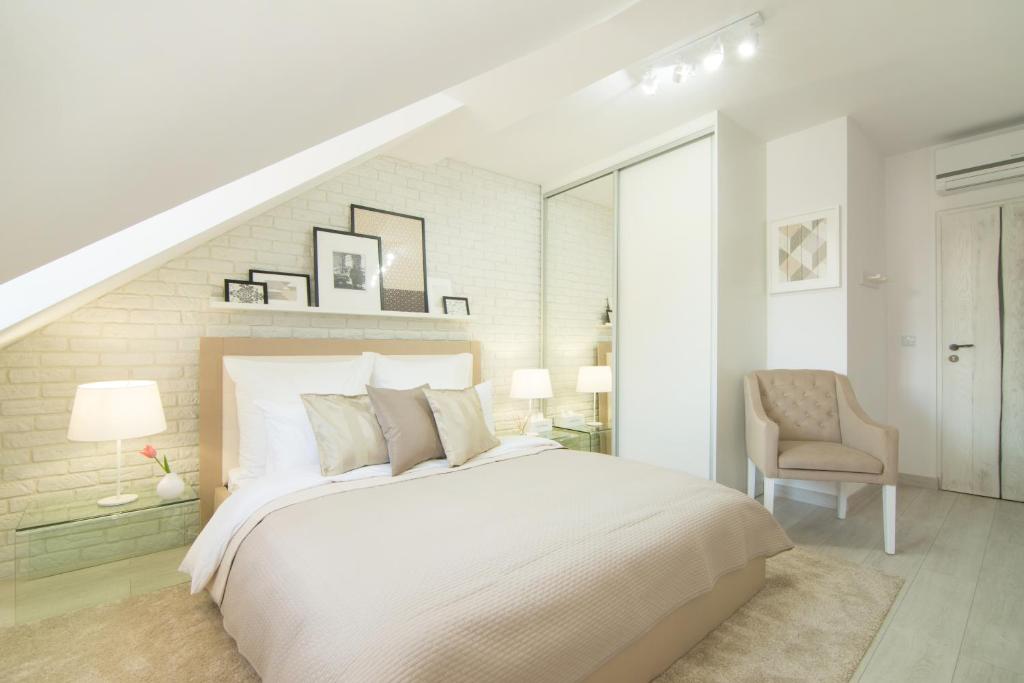 a white bedroom with a bed and a chair at Apartamenty "Starówka" in Kazimierz Dolny