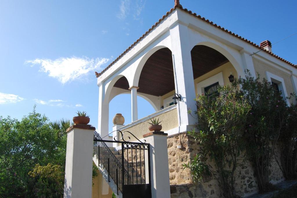 a white building with an arch and a fence at Spiti Limnos, Idyllisch Gelegen Im Orangenhain in Límnos