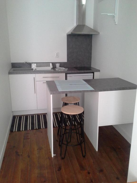 une cuisine avec un comptoir, une table et des tabourets dans l'établissement Agréable studio à proximité du centre ville, à Tarbes