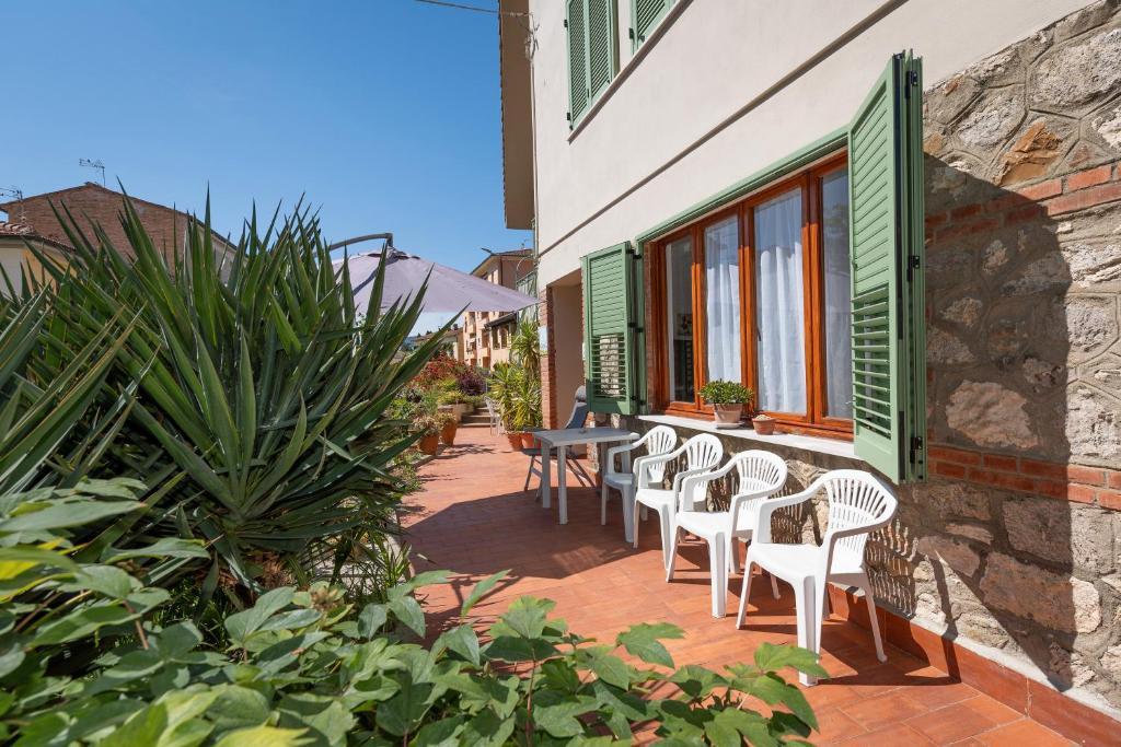 a patio with white chairs and a table and windows at Casa Baldi Lajatico in Laiatico