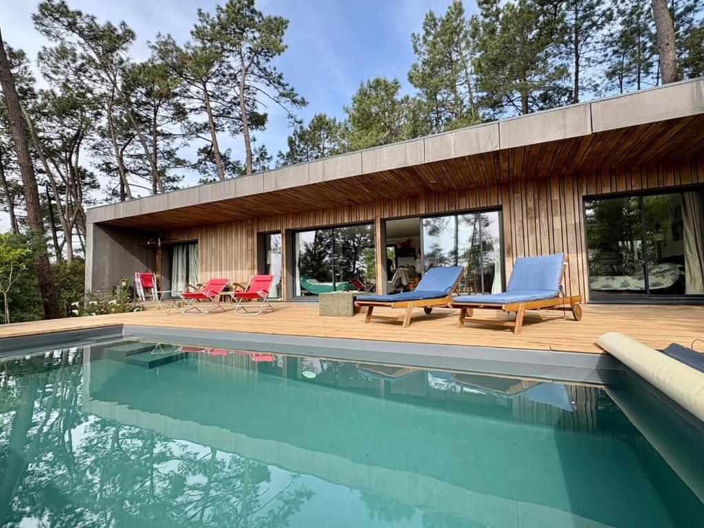 une maison avec une piscine et des chaises dans l'établissement La Villa du Bout du Monde, Pool & Jacuzzi, à Soorts-Hossegor