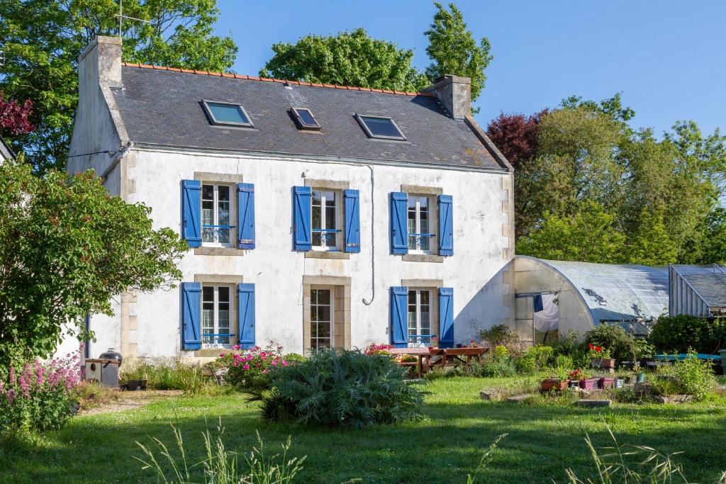 an old house with blue shutters and a garden at La ferme de séjour du Cosquer in Beuzec-Cap-Sizun