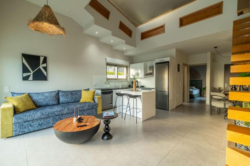 a living room with a blue couch and a kitchen at Jarko Luxury Houses in Argoulidhés