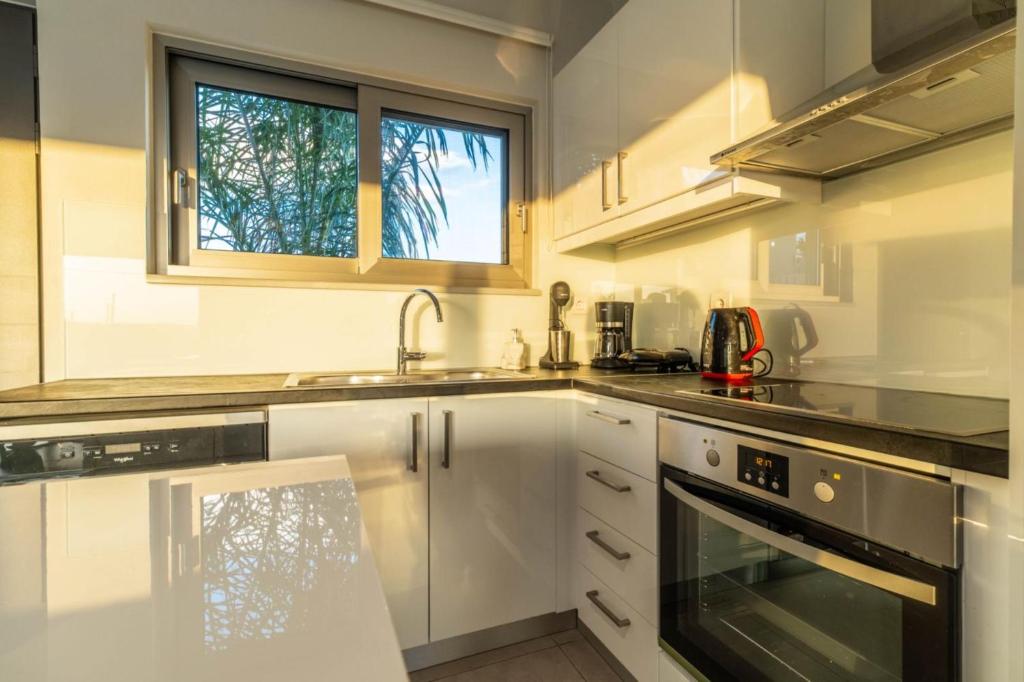 a kitchen with white cabinets and a sink and a window at Jarko Luxury Houses in Argoulidhés