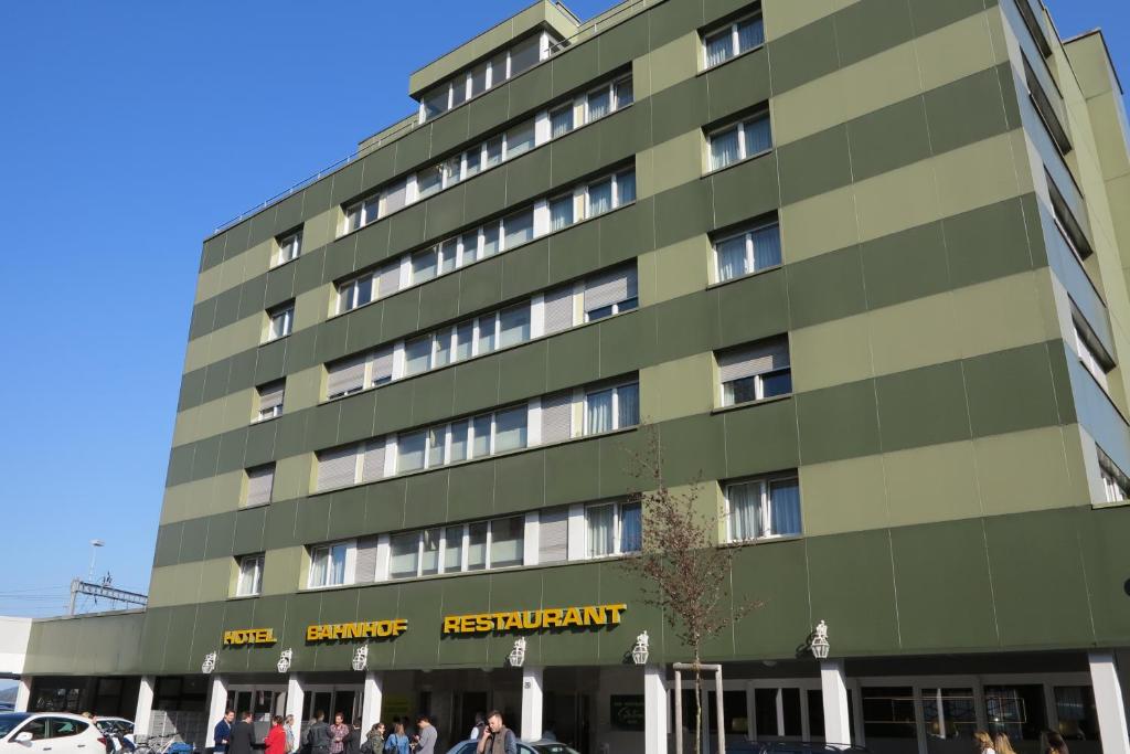 a large green building with people walking in front of it at Hotel Bahnhof in Uzwil