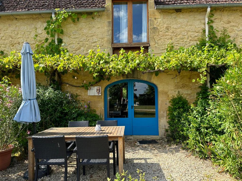 une table avec une porte bleue et un parasol dans l'établissement Hameau du Soleil -Hibou, à Sainte-Mondane