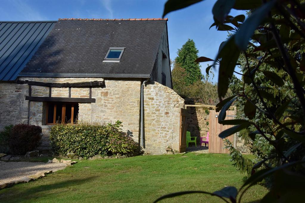 une maison en pierre avec un toit noir et une cour dans l'établissement Charmant gîte breton authentique, à Séglien