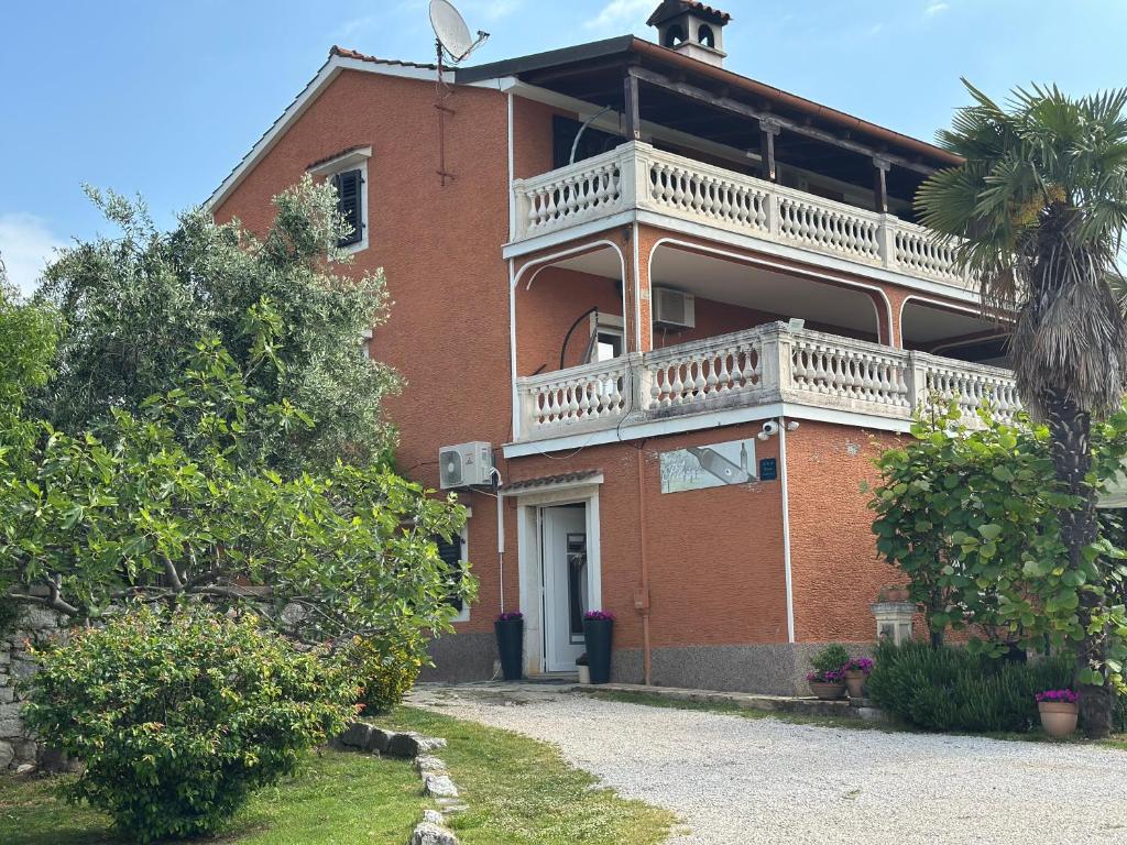 une maison en briques rouges avec un grand balcon dessus dans l'établissement Apartment Peloža 1, à Poreč