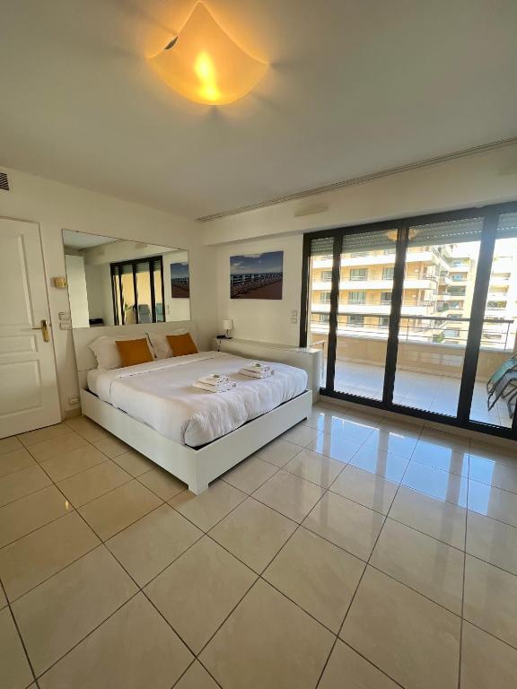 - une chambre avec un lit blanc et de grandes fenêtres dans l'établissement Studio Palais de la Méditerranée, à Nice