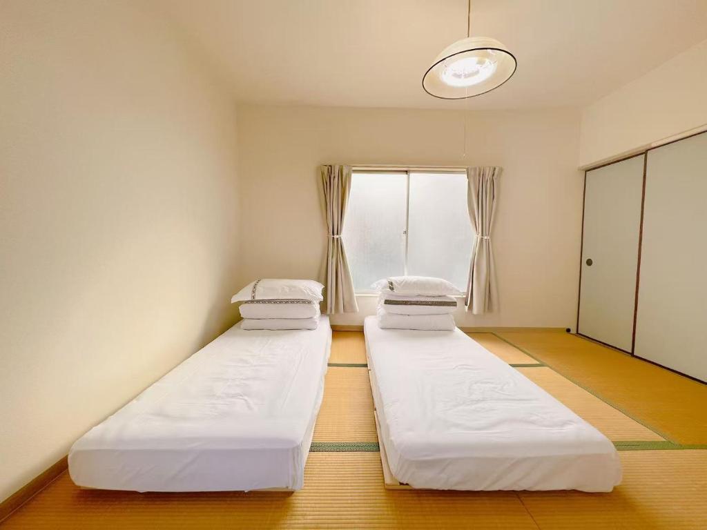 zwei Betten in einem Zimmer mit Fenster in der Unterkunft 友縁の家Destined Bonds Haven西巣鴨 in Tokio
