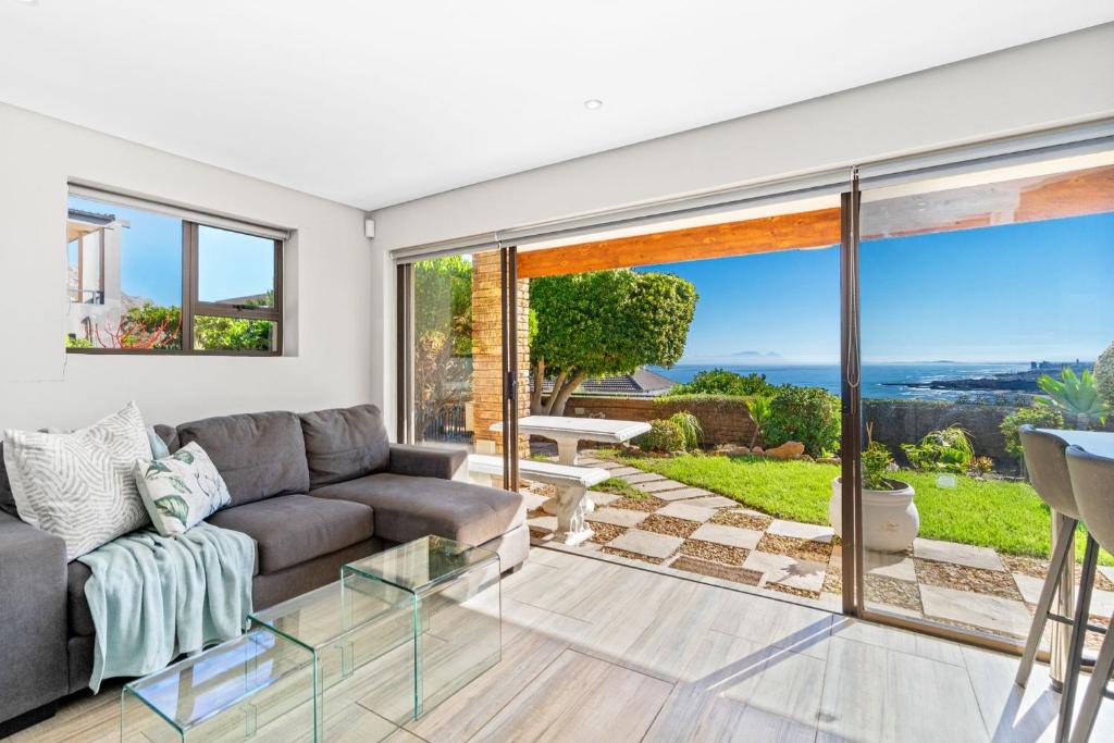 a living room with a couch and a view of the ocean at Zaria Sun Cottage by Host Agents in Gordonʼs Bay