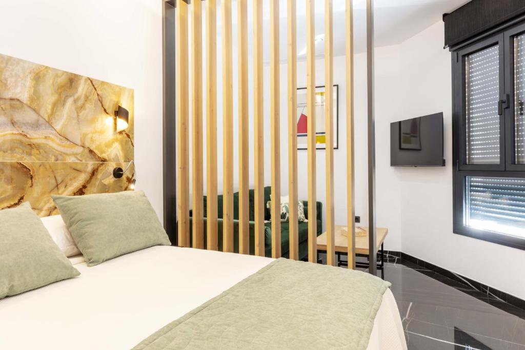 ein Schlafzimmer mit einem Bett und einem hölzernen Kopfteil in der Unterkunft Un acogedor complejo compuesto de 5 apartamentos in Barbate