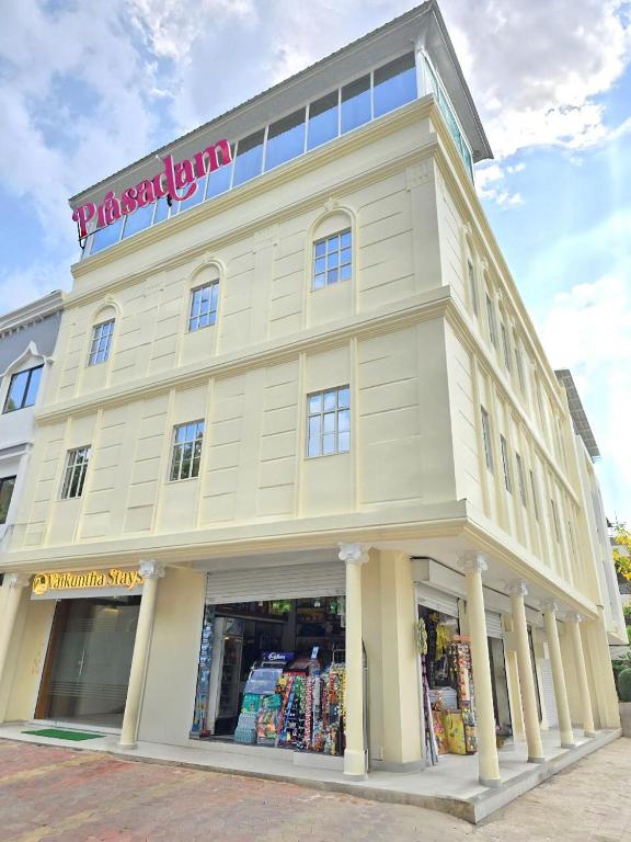 a large white building with a store front at Vaikuntha Stays Hotel in Indore