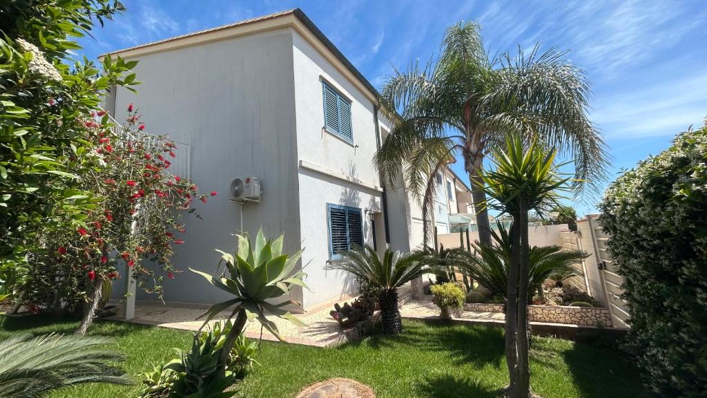 una casa bianca con palme nel cortile di Mare Nostrum Apartment a Marina di Ragusa