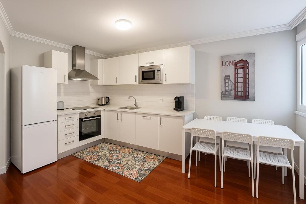 a kitchen with white cabinets and a table and chairs at Apartamento de 2 habitaciones en la zona centro. in Castro-Urdiales