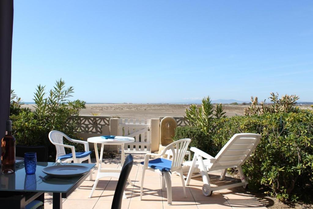 une terrasse avec une table et des chaises et la plage dans l'établissement Appartement vue mer 3 pièces - Gruissan Ayguades AY110-M04, à Narbonne-Plage