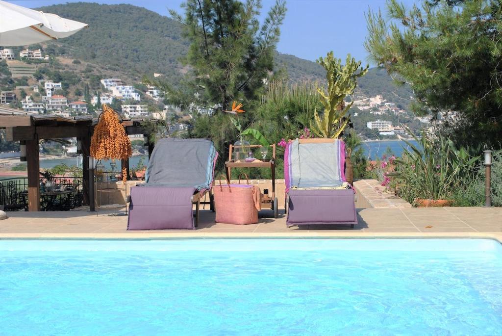 two lounge chairs sitting next to a swimming pool at The Poros Villa in Poros