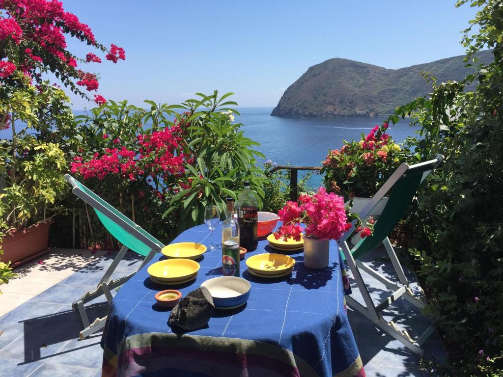 a blue table with yellow dishes and flowers on a balcony at Flach D in Lipari