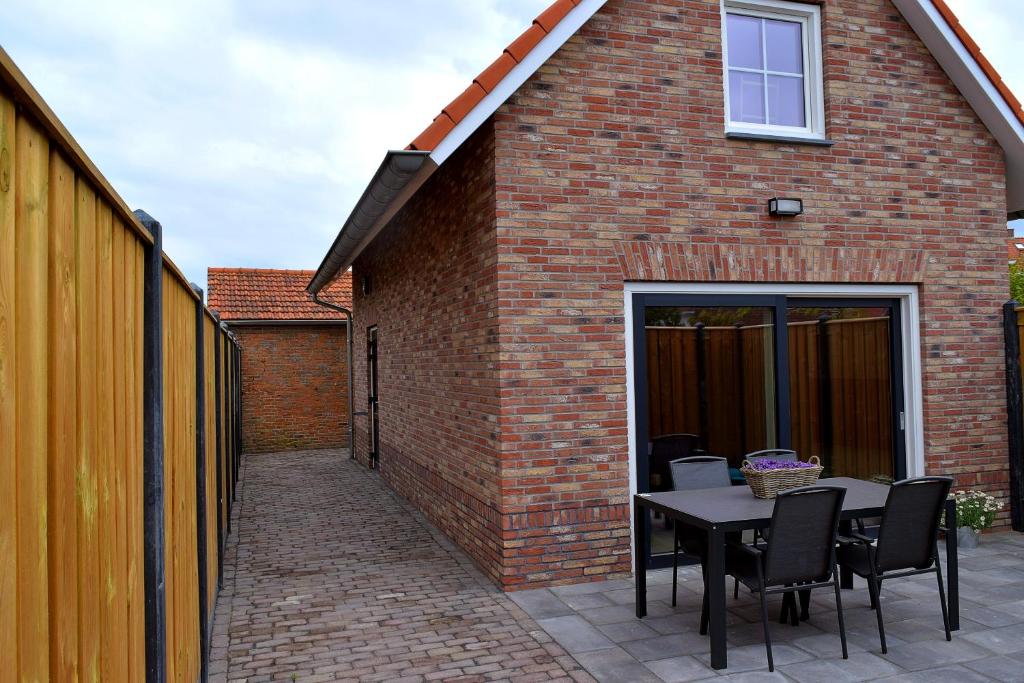 ヴェストカペレにあるVakantiehuis de Casembrootのレンガ造りの建物の前にパティオ(テーブル、椅子付)