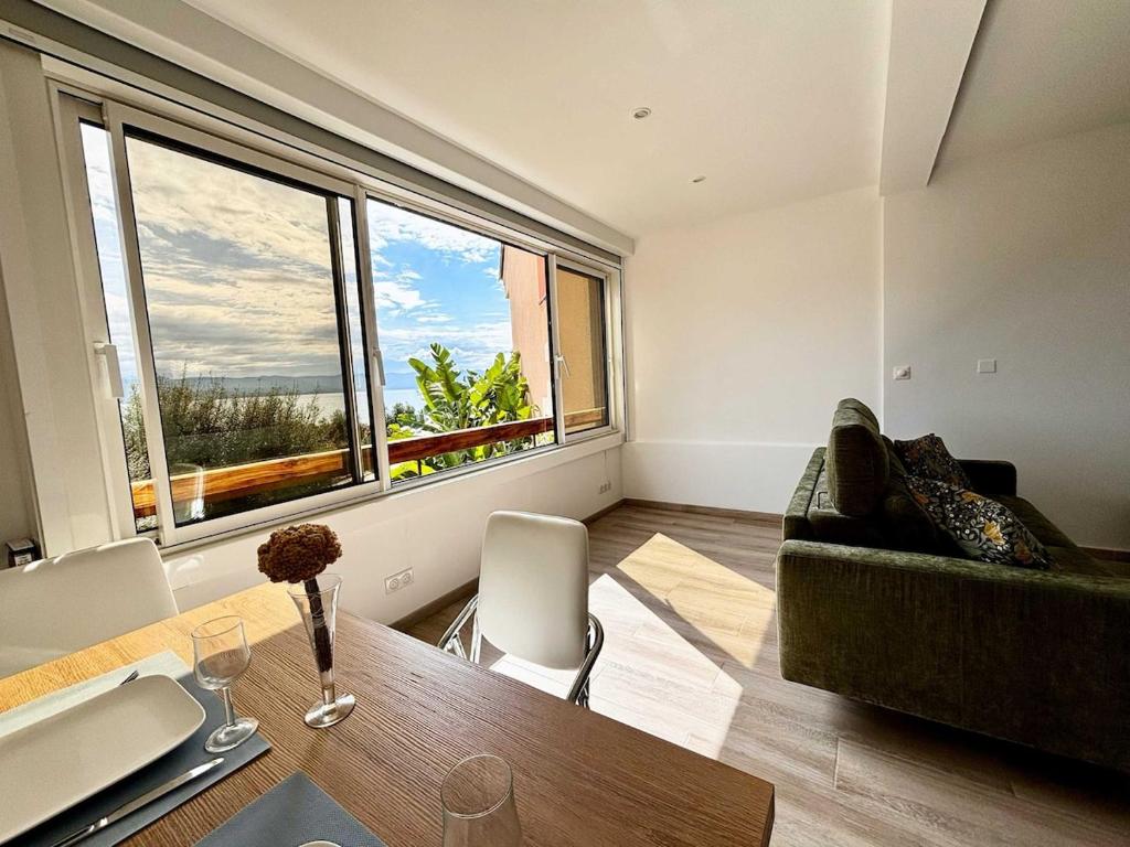 un salon avec un canapé et une grande fenêtre dans l'établissement Casamea - Studio vue mer, 2 min plage, Clim, à Ajaccio