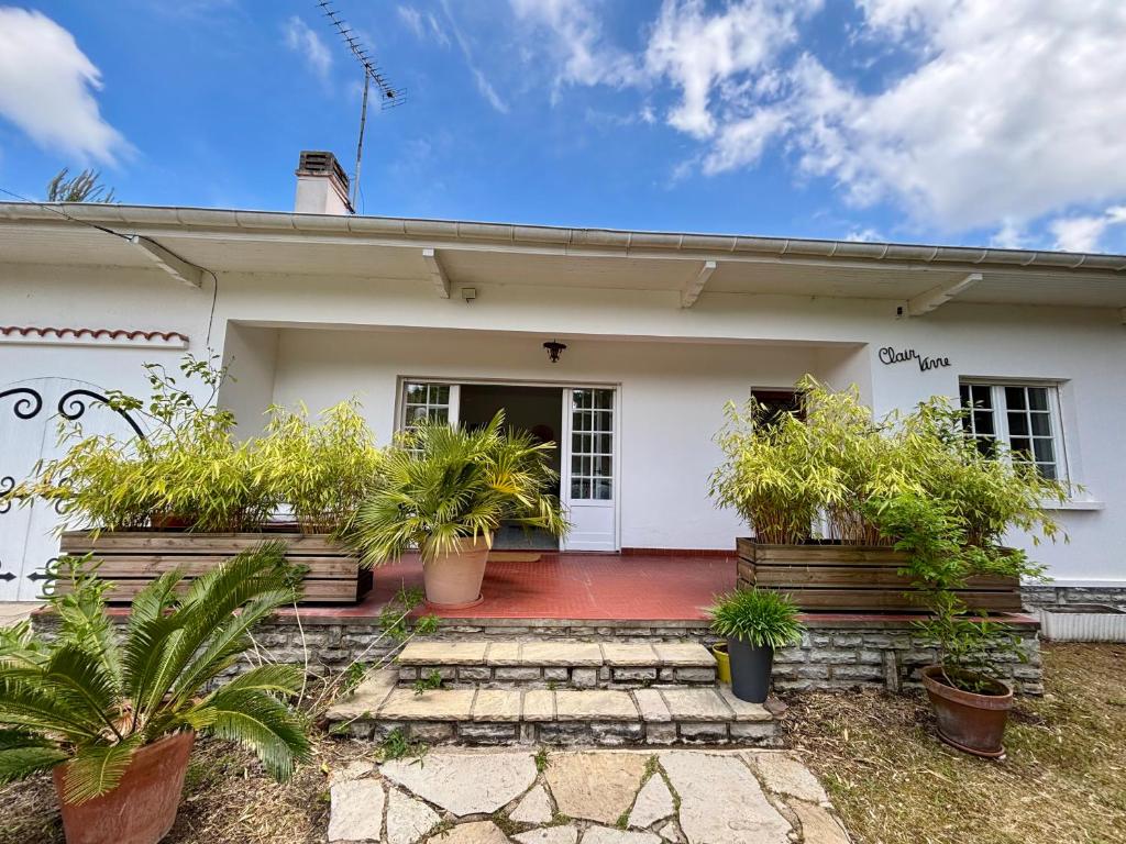 une maison blanche avec des plantes en pot devant elle dans l'établissement Maison à 4km de Hossegor, à Bénesse-Maremne