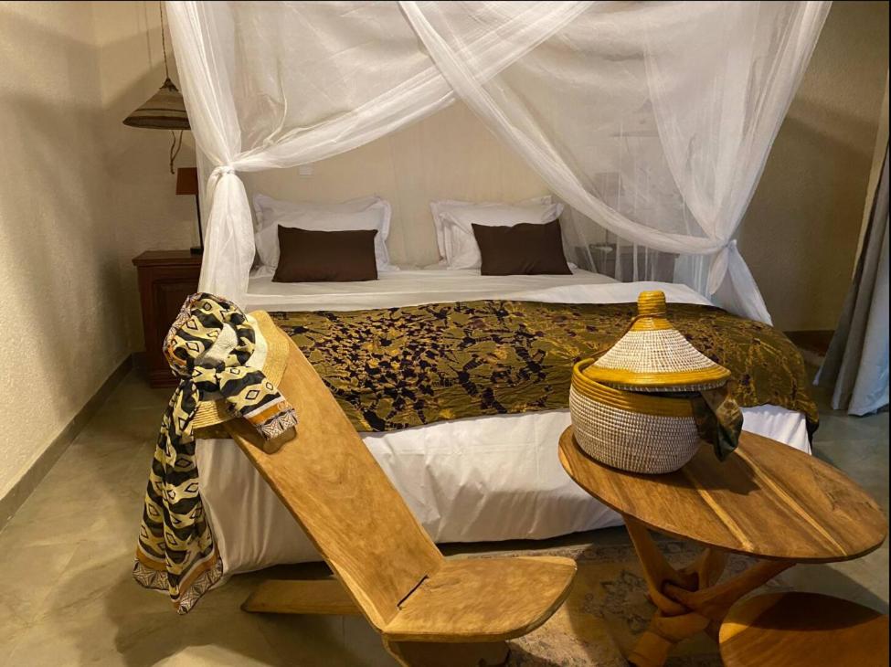 a bedroom with a bed and a table with a chair at Toubacouta Lodges in Toubakouta