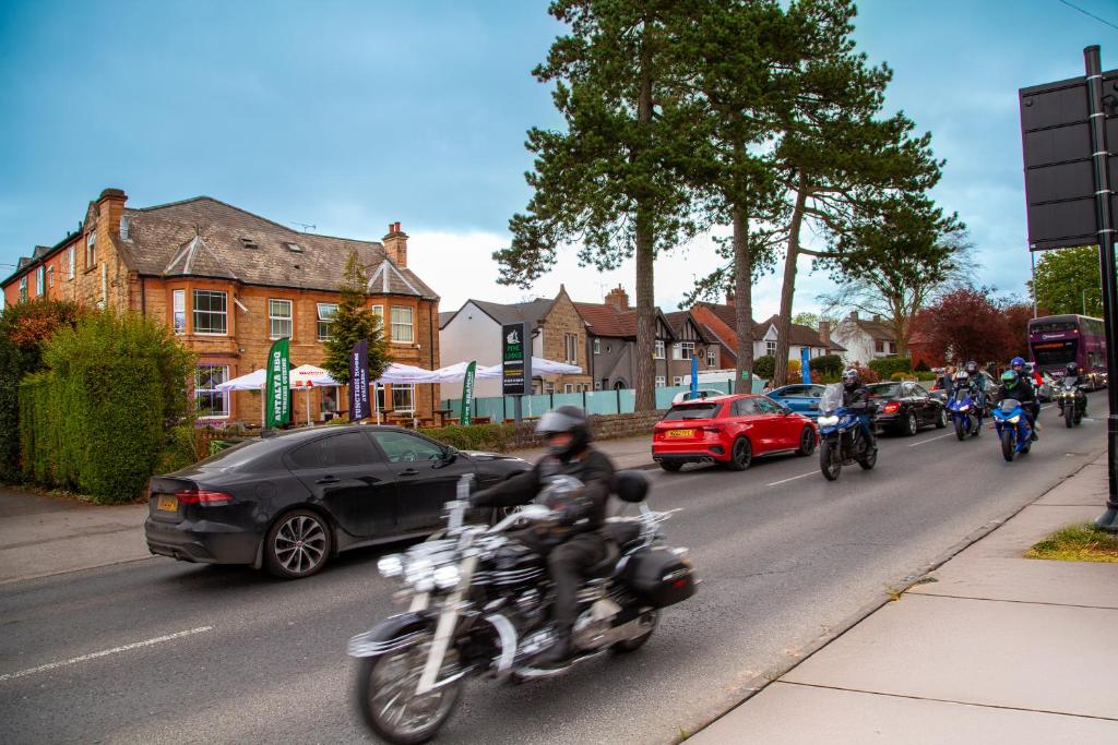 a group of people riding motorcycles down a street at Pine Lodge Hotel & Restaurant Mansfield in Mansfield