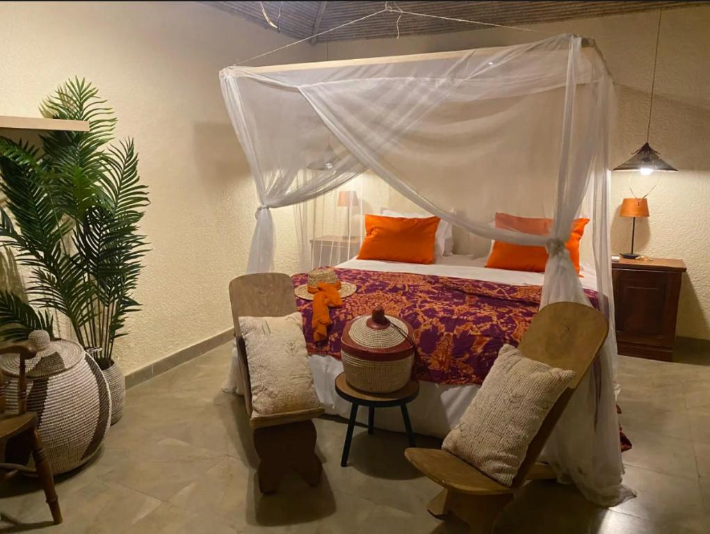 a bedroom with a canopy bed and two chairs at Toubacouta Lodges in Toubakouta