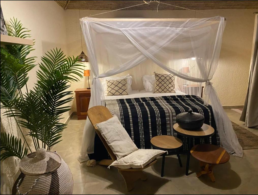 a bedroom with a bed and a chair and a table at Toubacouta Lodges in Toubakouta