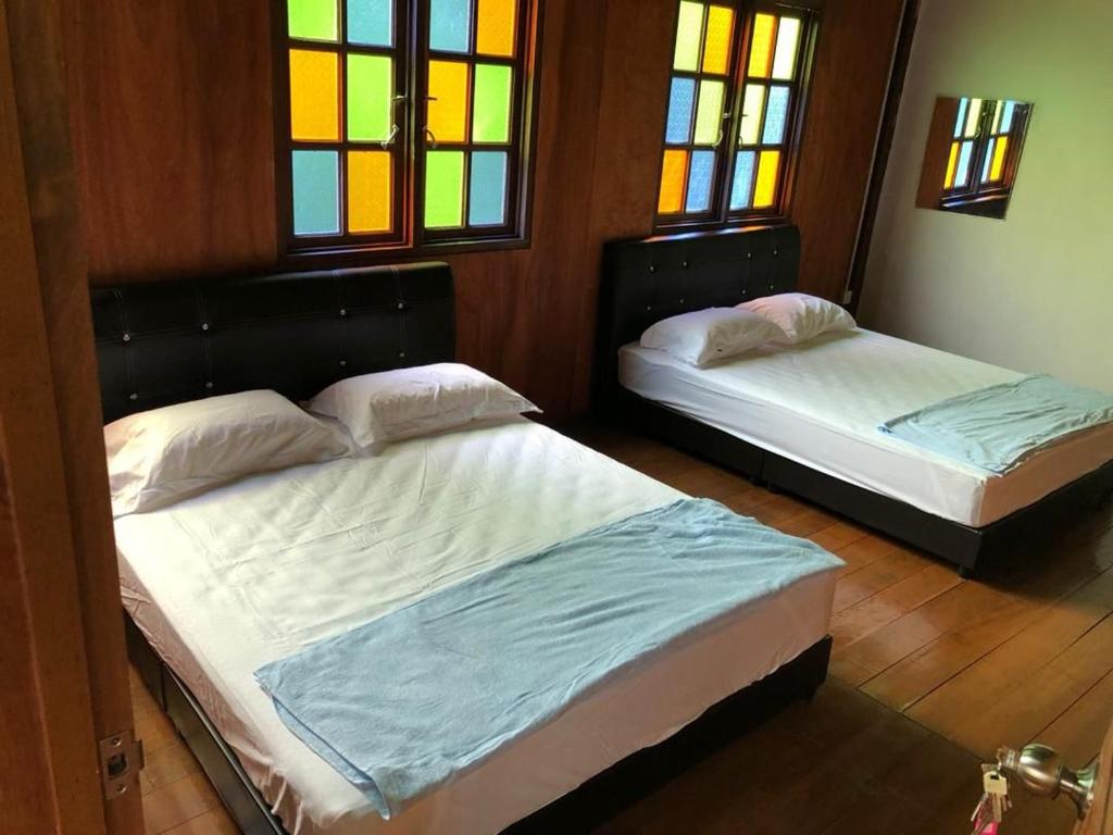 バリック・プラウにあるQuadruple Traditional Wooden GuestHouseのステンドグラスの窓が備わる客室内のベッド2台